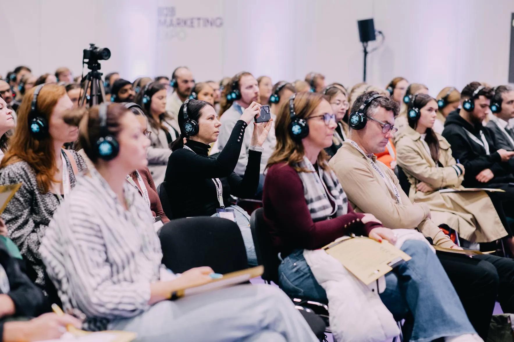 Engaged audience at the B2B Marketing Expo 2025 using headphones to connect.